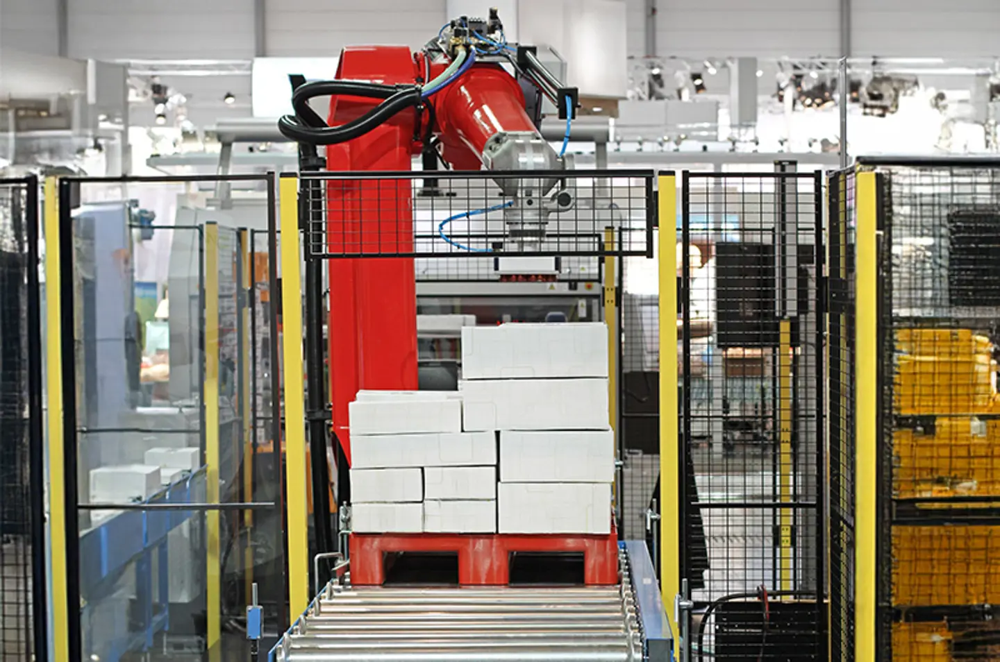 Industrielt transportbåndssystem i en fabrik med sikkerhedsbarrierer og advarselsstriber på gulvet