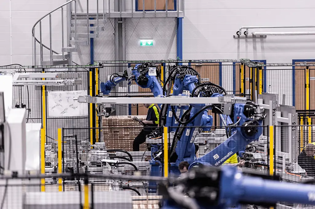 Robotarme palleterer kartoner inde i en beskyttet automatiseringscelle